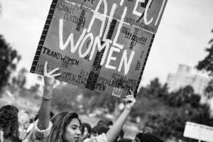 photo of woman holding up a sign that says Respect All Women